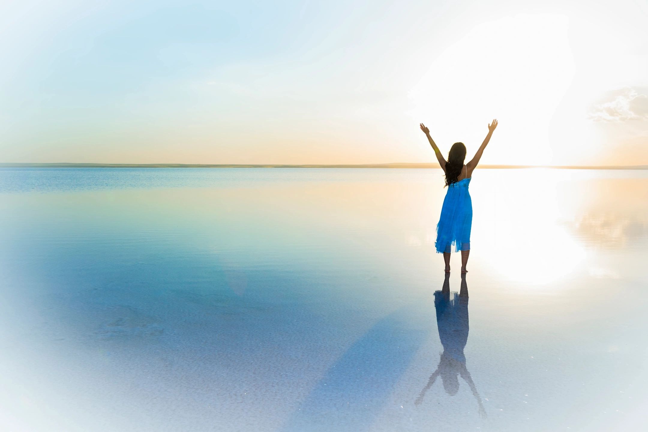 Woman with arms raised at beach — freedom and transformation